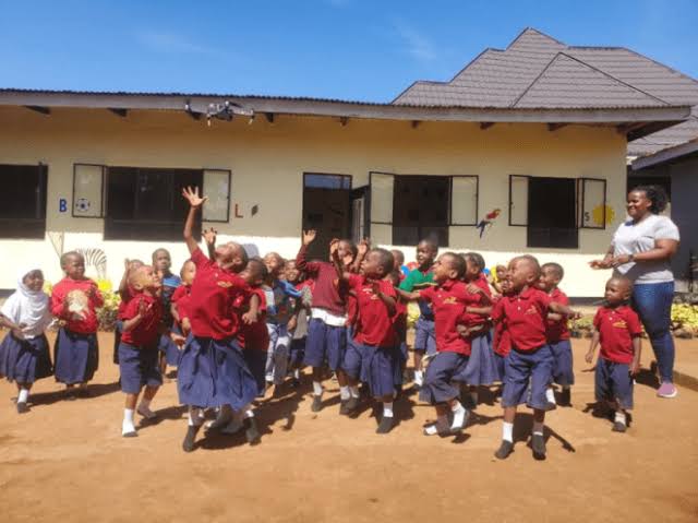 Smiling children or a group of learners with teachers outdoors in a hopeful, bright setting